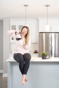 Woman sitting on kitchen counter and pouring a cup of coffee during her branding photoshoot in Ottawa