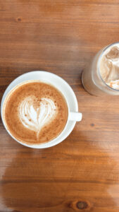 Photo of a latte in a white cup on a brown wooden table